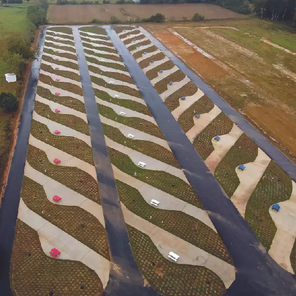 Aerial photo of a newly built RV park with rows of curved concrete pads, paved lanes, and colorful picnic tables.